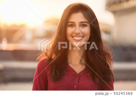 Smiling happy girl looking at camera, walking in city Smiling happy girl looking at camera, walking in city 50245369