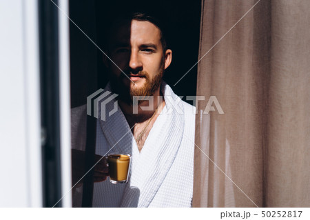Male in white bathrobe with coffee mug in hand. Male in white bathrobe with coffee mug in hand. 50252817