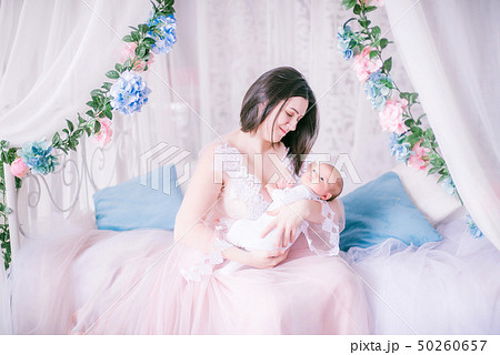 Young mother in a boudoir dress with a baby Young mother in a boudoir dress with a baby 50260657