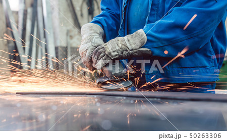 Worker in metal factory grinding workpiece with sparks flying Worker in metal factory grinding workpiece with sparks flying 50263306