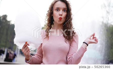 Portrait of a smiling excited girl holding cotton candy at amusement park Portrait of a smiling excited girl holding cotton candy at amusement park 50265360