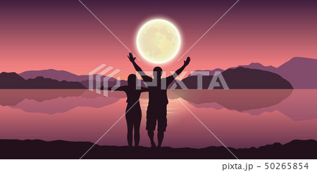 happy couple with arms raised enjoy the full moon and mountain landscape by the lake 50265854