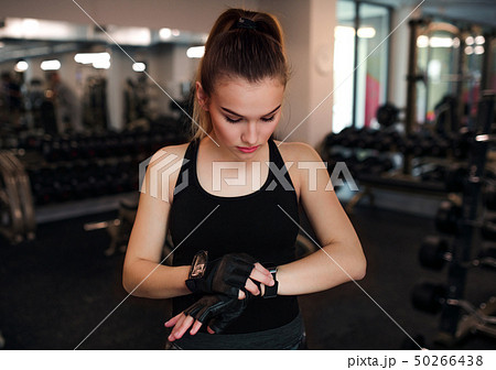 Young girl or woman putting on gloves in gym. 50266438
