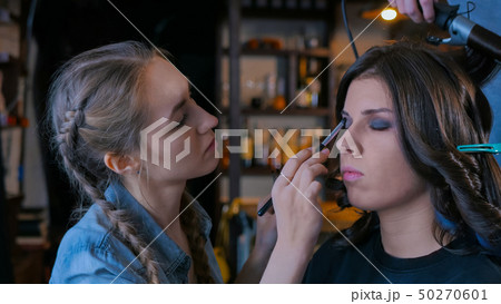 Make-up artist and hairdresser working with woman client Make-up artist and hairdresser working with woman client 50270601