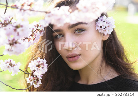 Girls face in frame of blossom tree branch outdoor Girls face in frame of blossom tree branch outdoor 50273214