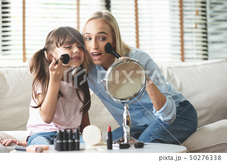Mom and Daughter applying cosmetic with brushes. 50276338
