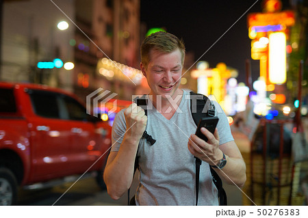 Happy tourist man backpacker using phone and getting good news in the busy street of Chinatown Happy tourist man backpacker using phone and getting good news in the busy street of Chinatown 50276383