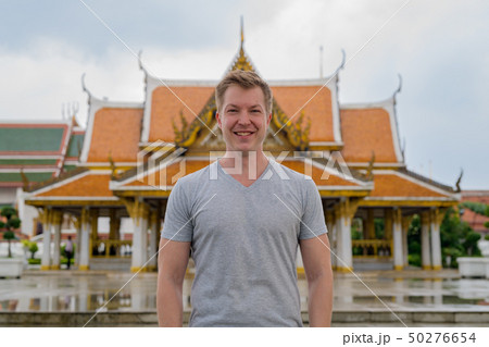 Young happy tourist man smiling against view of the Buddhist temple in Bangkok 50276654
