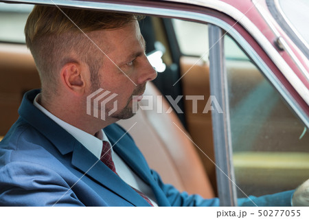 Portrait of blonde businessman driving vintage car Portrait of blonde businessman driving vintage car 50277055