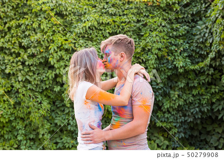 Holiday, holi and people concept - Happy couple having fun with multicolored powder on their faces Holiday, holi and people concept - Happy couple having fun with multicolored powder on their faces 50279908