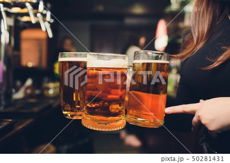 Womans hand pouring pint of beer behind the bar. Womans hand pouring pint of beer behind the bar. 50281431