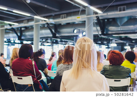 People sit in armchairs in conference room, focus on blonde woman nape. People sit in armchairs in conference room, focus on blonde woman nape. 50281642
