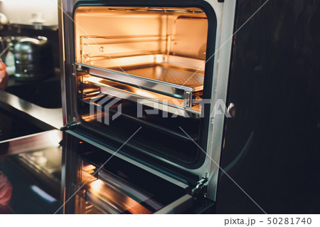 Empty open electric oven with hot air ventilation. New oven. Door is open and light is on. 50281740