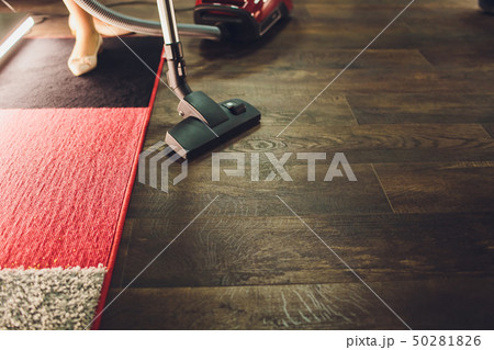 Dark head of a modern vacuum cleaner being used while vacuuming a rug. Cleaning service concept Dark head of a modern vacuum cleaner being used while vacuuming a rug. Cleaning service concept 50281826