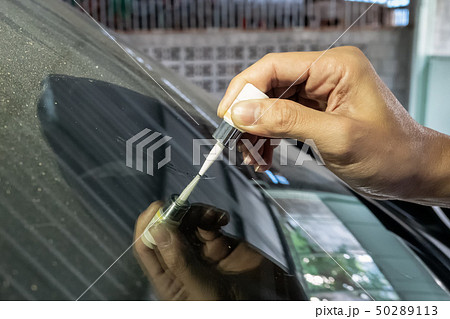 Man mechanic using glue welding cracked windshield Man mechanic using glue welding cracked windshield 50289113