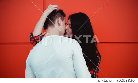 Couple kissing against isolated red wall in the city Couple kissing against isolated red wall in the city 50293830