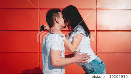 Couple kissing against isolated red wall in the city 50293959