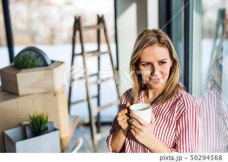 A young woman moving in new home, drinking coffee. 50294568