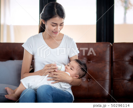 Asian mother feeding milk to her baby by bottle, t Asian mother feeding milk to her baby by bottle, t 50296114