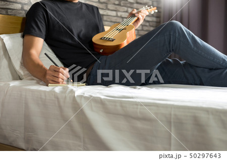 Happy young asian man playing ukulele sitting on Happy young asian man playing ukulele sitting on 50297643