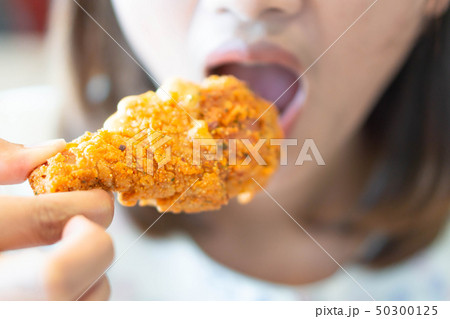 Close up woman eating fried chicken legs 50300125