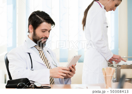 Doctor and his assistant in clinic Doctor and his assistant in clinic 50308413