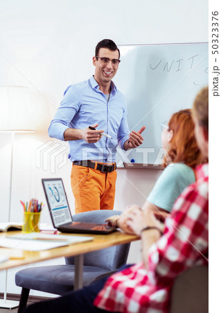 Positive cheerful young man smiling to students 50323376