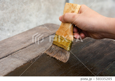 hand holding a brush Painting wooden timber boards hand holding a brush Painting wooden timber boards 50335205