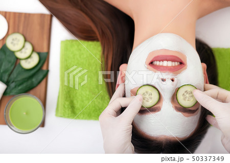 Beautiful woman having clay facial mask apply by beautician. 50337349