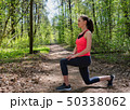 Fitness woman doing front lunge before run in summer forest 50338062