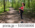 Woman runner doing warm-up exercise before jogging in forest 50338066
