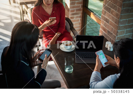 Women using phones in a bar Women using phones in a bar 50338145