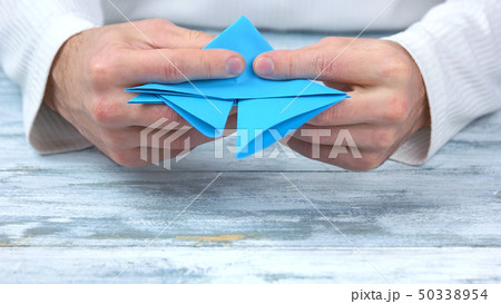 Close up male hands folding origami figure. 50338954