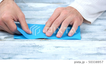 Close up hands folding blue paper sheet. Close up hands folding blue paper sheet. 50338957
