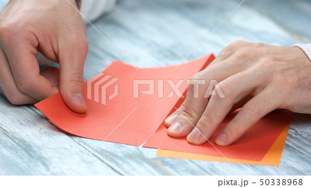 Man creating origami with red paper close up. 50338968