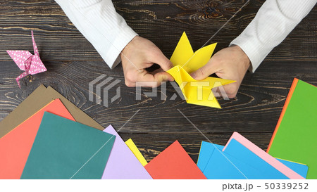 Male hands folding yellow paper sheet. 50339252