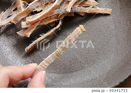 指でつまんだアタリメ(スルメ)。 50341755