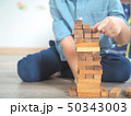 Small kid playing with wooden blocks on the floor 50343003