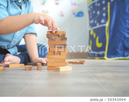 Small kid playing with wooden blocks on the floor Small kid playing with wooden blocks on the floor 50343004