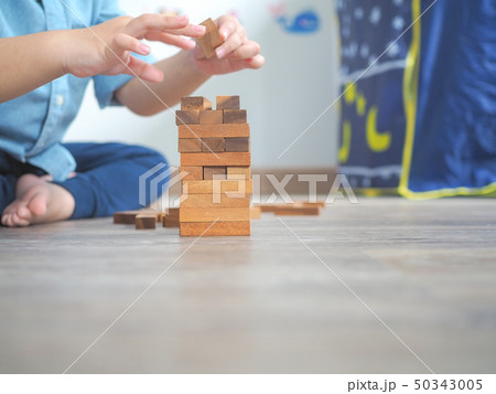 Small kid playing with wooden blocks on the floor 50343005
