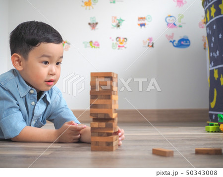 Small kid playing with wooden blocks on the floor Small kid playing with wooden blocks on the floor 50343008