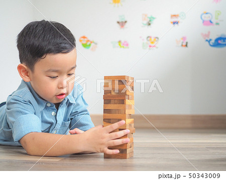 Small kid playing with wooden blocks on the floor Small kid playing with wooden blocks on the floor 50343009