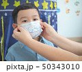 A mother wearing protective mask for her kid to 50343010