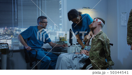 Soldier sitting in wheelchair among doctors 50344541