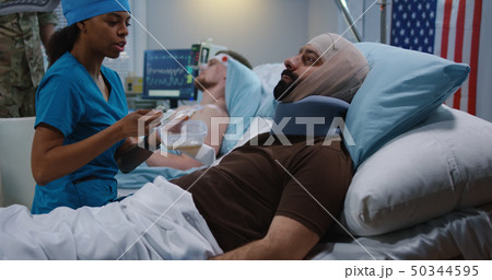 Nurse feeding injured soldiers in hospital bed Nurse feeding injured soldiers in hospital bed 50344595