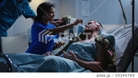 Nurse feeding injured soldier in hospital bed 50344769