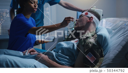 Nurse feeding injured soldier in hospital bed 50344792
