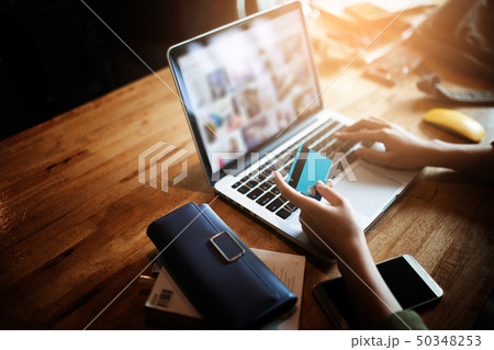 Young woman holding credit card and using laptop Young woman holding credit card and using laptop 50348253