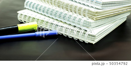 notebooks and two markers on black background. 50354792