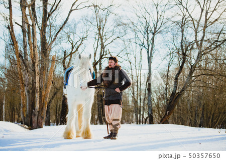 Man in suit of ancient warrior walking with the big white horse Man in suit of ancient warrior walking with the big white horse 50357650